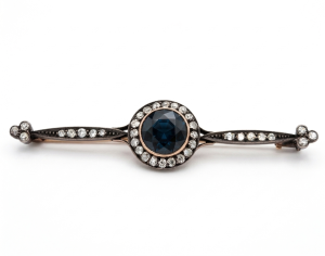 An antique gold brooch studded with diamonds and an impressive central sapphire stone